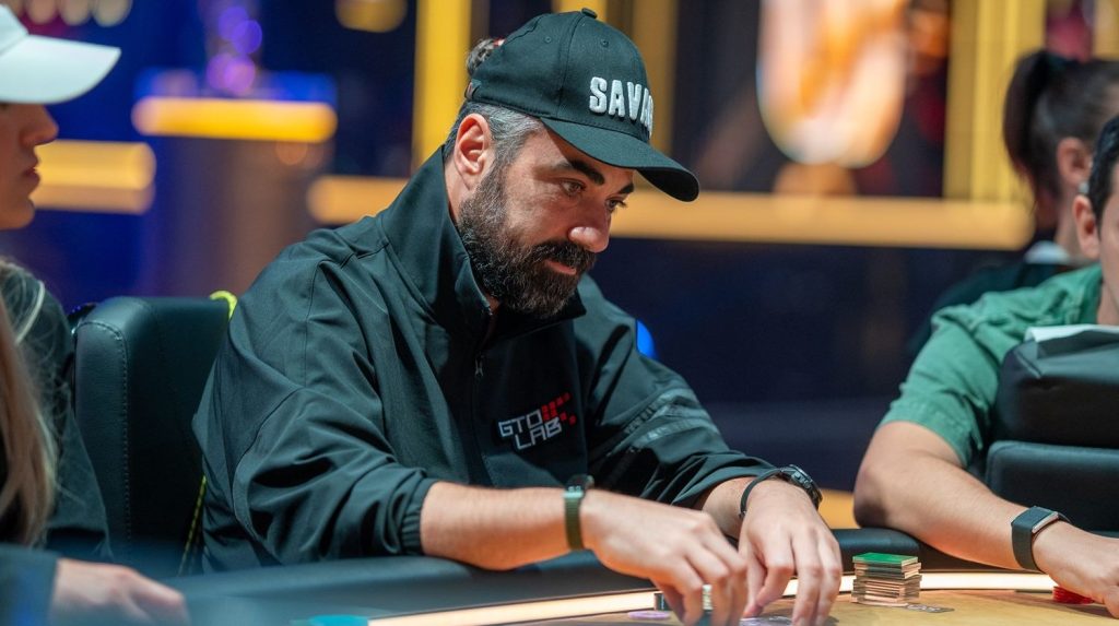 Orpen Kisacikoglu playing at the Triton Poker Series, wearing a GTO LAB jacket and black cap, focusing on his chips during a hand.