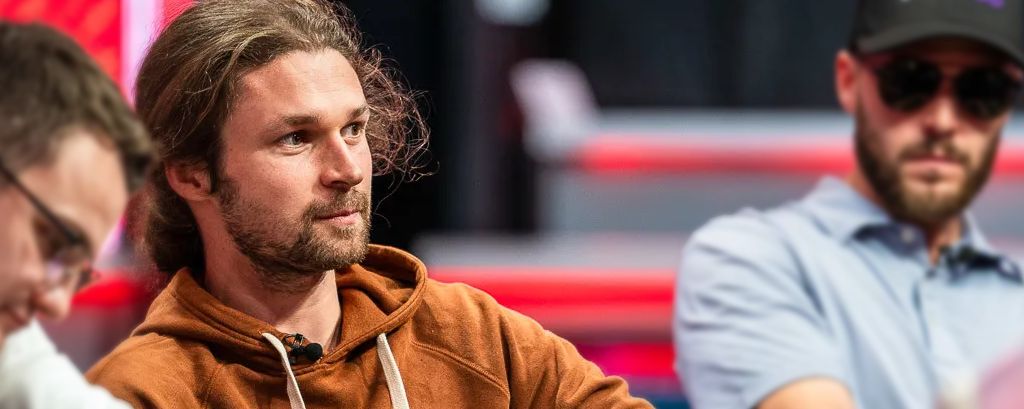 Professional poker player Ben Heath focused at a live tournament table wearing a brown hoodie.